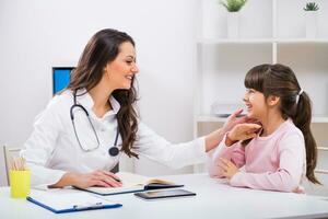 vrouw dokter en kind pratend Bij de medisch kantoor foto