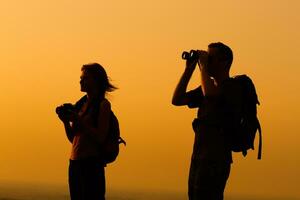 paar met rugzak aan het kijken de zonsondergang foto