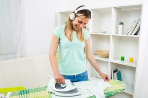mooi vrouw strijken kleren en luisteren muziek- Bij haar huis foto