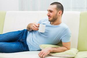 jong Mens geniet drinken koffie Bij huis foto