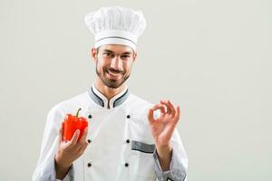 chef is tonen groenten en OK teken Aan grijs achtergrond foto