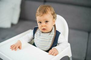 portret van schattig baby jongen zittend in een hoog stoel foto