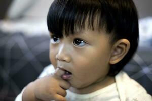 aanbiddelijk weinig Aziatisch baby jongen zuigen vinger in mond foto