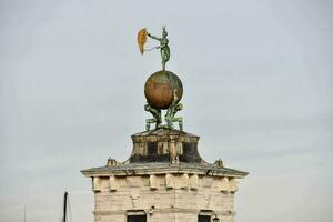 een standbeeld van mensen Holding een groot bal Aan top van een toren foto