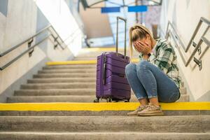 bezorgd vrouw zittend Aan een trap Bij de trein station foto