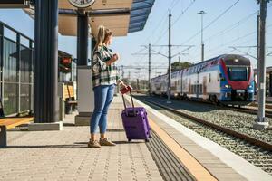 vrouw met koffer en ticket Aan een trein station drinken koffie foto