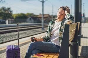 moe vrouw met koffie slapen Aan een bank Bij de trein station foto