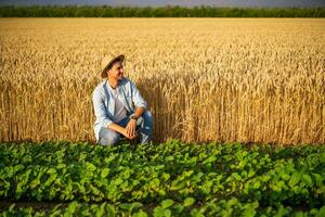 gelukkig boer geniet in zijn groeit tarwe en soja veld- foto