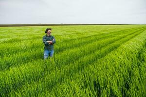 gelukkig boer is staand in zijn groeit tarwe veld- foto