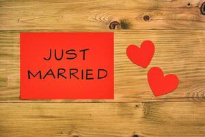 tekst alleen maar getrouwd en hart vormen Aan de rood papier Aan houten tafel foto
