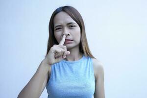 Aziatisch vrouw covers haar neus- met haar vinger foto