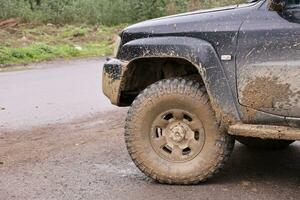 wiel detailopname in een platteland landschap met een modder weg. van de weg af 4x4 suv auto- met ditry lichaam na rit in modderig weg foto