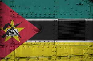 Mozambique vlag afgebeeld Aan kant een deel van leger gepantserd tank detailopname. leger krachten conceptuele achtergrond foto