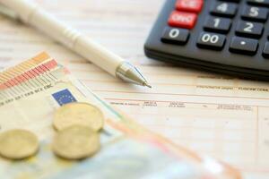 vulling Italiaans belasting het formulier werkwijze met pen, rekenmachine en euro geld rekeningen dichtbij omhoog. belasting betalen periode foto