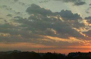 mooi zonsopkomst met warm oranje zonlicht en balken door blauw lucht foto