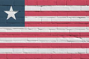 Liberia vlag afgebeeld in verf kleuren Aan oud steen muur. getextureerde banier Aan groot steen muur metselwerk achtergrond foto
