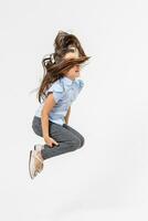 gelukkig schoolmeisje jumping hoog Aan wit achtergrond foto