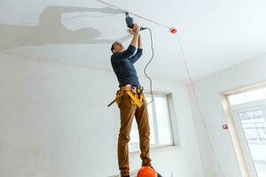 dertig jaar oude arbeider met stukadoorsgereedschap in een huis. stukadoor renovatie van binnenmuren en plafonds met vlotter en pleisterwerk. foto