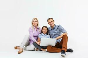 gelukkig familie aan het liegen naar beneden Aan de verdieping terwijl surfing Aan internet online met laptop, geïsoleerd over- wit foto