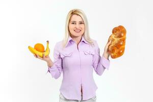 jong mooi en gelukkig meisje met lang haar- houdt bananen Aan haar Rechtsaf hand- en een bun Aan haar links hand, geïsoleerd over- wit achtergrond foto