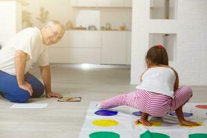 weinig meisje en opa Speel twister Bij huis foto