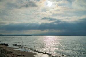 zonsondergang Aan de west strand Aan de Baltisch zee. golven, strand, bewolkt lucht en zonneschijn foto
