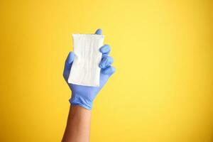 blauw schoonmaak handschoenen met een spons tegen een geel achtergrond foto