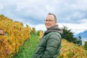 buitenshuis portret van midden- leeftijd 55 - 60 jaar oud Mens genieten mooi hoor herfst dag in wijngaarden, gezond en actief levensstijl foto