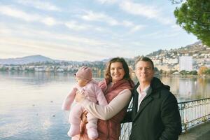 buitenshuis portret van gelukkig jong paar met aanbiddelijk baby meisje genieten van mooi hoor visie van winter meer Genève of lak leman, Montreux, Zwitserland foto