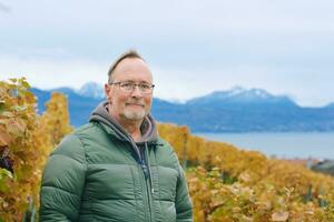 buitenshuis portret van midden- leeftijd 55 - 60 jaar oud Mens genieten mooi hoor herfst dag in wijngaarden, gezond en actief levensstijl foto