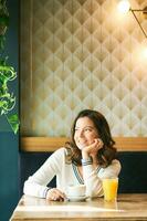 portret van gelukkig gezond vrouw hebben koffie en oranje sap in cafe foto