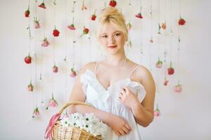 studio portret van mooi jong tiener- 15 - 16 jaar oud meisje vervelend zomer jurk, poseren Aan wit achtergrond met hangende rozen, Holding mand met madeliefje bloemen, schoonheid en mode concept foto