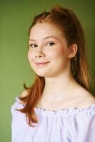 schoonheid portret van mooi jong 15 - 16 jaar oud roodharige tiener meisje vervelend Purper jurk poseren Aan groen achtergrond foto