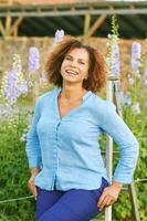 buitenshuis portret van mooi 50 jaar oud vrouw genieten van mooi hoor dag in bloem park of tuin, gelukkig en gezond levensstijl foto