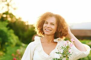 buitenshuis dichtbij omhoog portret van mooi midden- leeftijd vrouw Bij zonsondergang foto