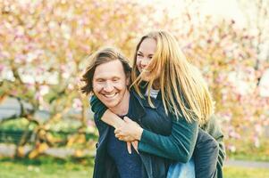 buitenshuis portret van gelukkig romantisch stel, vrouw zittend Aan terug van haar vriend, gelukkig relaties foto