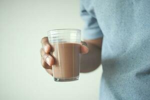 Mens hand- Holding glas van chocola melk foto