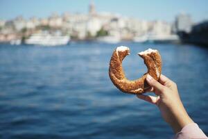 Dames Holding een Turks bagel simit tegen Istanbul stad achtergrond foto