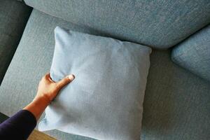 hand- houden zetten hoofdkussen Aan bank, schoonmaak sofa foto