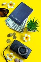 zomer reizen concept. paspoort, geld, zonnebril en een camera op een gele achtergrond. verticaal formaat