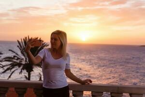 vrouw bewonderend zonsondergang van haar balkon foto