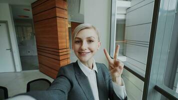 pov van jong zakenvrouw in pak nemen een selfie foto Holding smartphone en hebben pret in modern kantoor binnenshuis