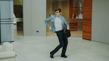 gek zakenman dansen met aktentas in modern lobby binnenshuis alleen foto