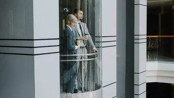 zakenvrouw en zakenman collega's pratend in in beweging lift in modern bedrijf centrum binnenshuis foto