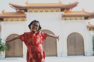 Aziatisch meisje vervelend rood Chinese pak geluk tegen China tempel achtergrond foto