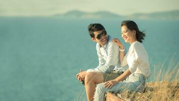 Aziatisch jonger paren ontspannende Bij zee kant foto
