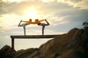 paren van vrouw spelen yoga houding Aan strand pier met morgen zon licht foto