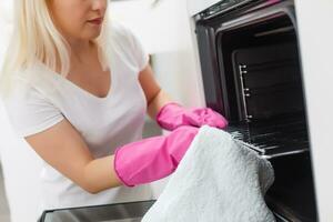 jong vrouw aan het doen huiswerk, schoonmaak de keuken foto