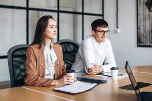 aantrekkelijke brunette koffie drinken, haar glazen collega luistert aandachtig naar de vergadering. foto