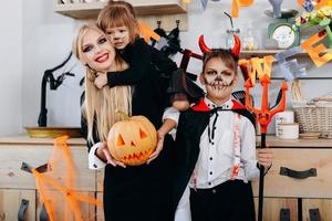 grappige familie in de keuken die in kostuum staat en naar de camera kijkt - halloween-concept foto